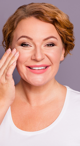 Woman in white shirt smiling and touching forehead