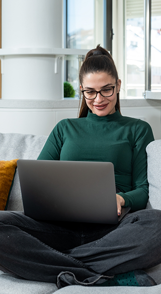 Woman sitting on couch typing on laptop
